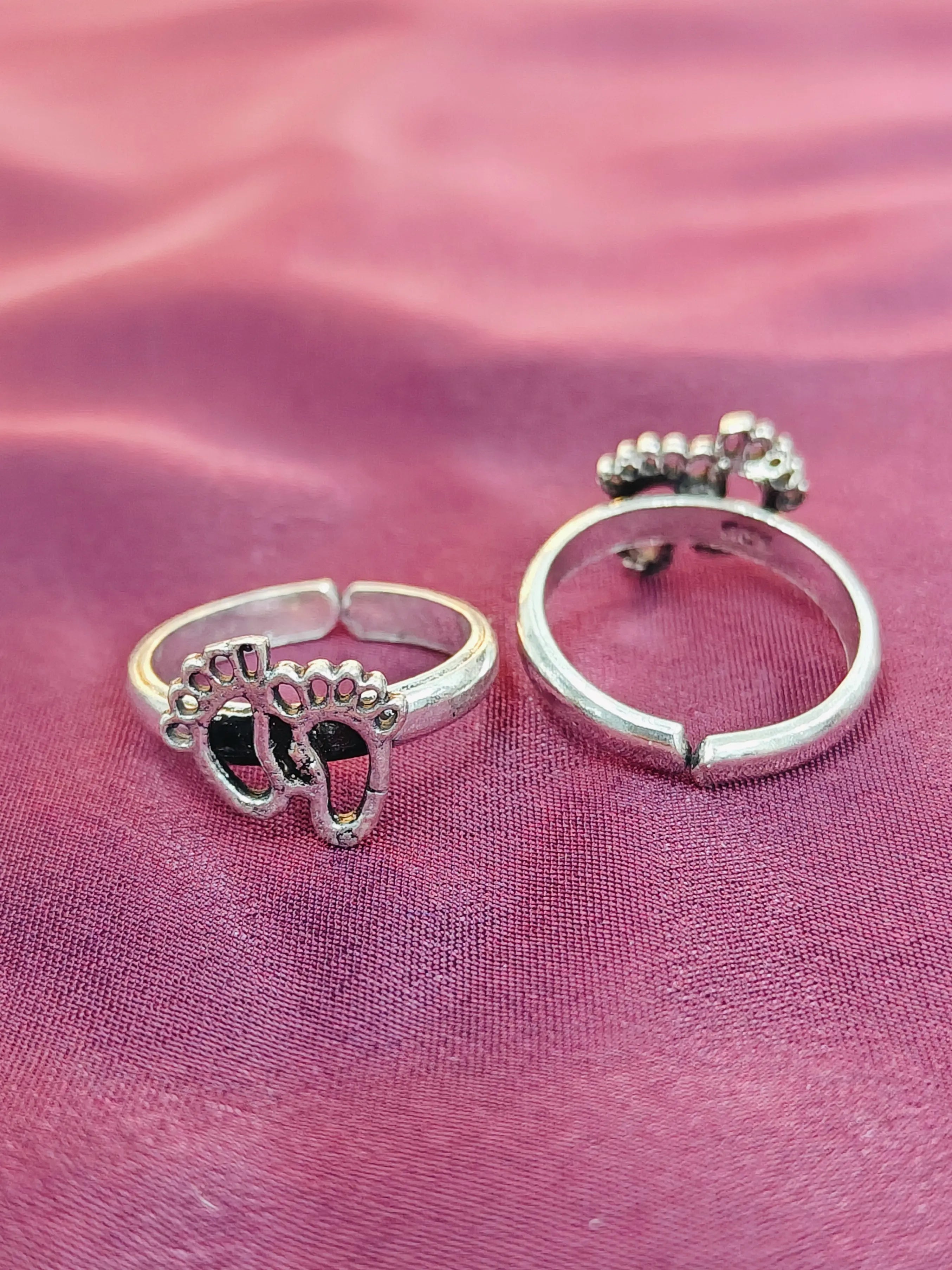 Two silver rings on a pink fabric background